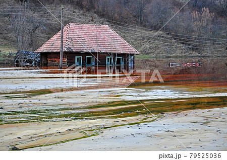 Ecological disaster. An abandoned village flooded by polluted water from a mine Ecological disaster. An abandoned village flooded by polluted water from a mine 79525036