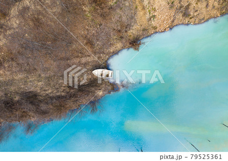 Aerial view of a boat in a turquoise lake contaminated with cyanide 79525361