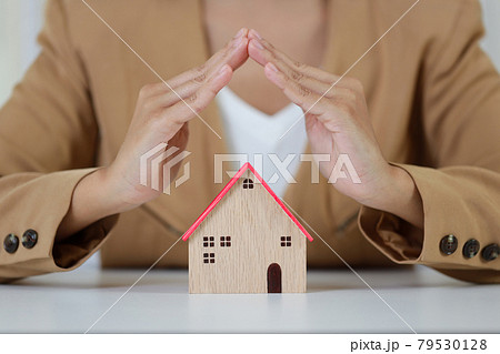 Young active business woman hands in casual dress sitting and protecting house model on white table. Property insurance and security concept 79530128
