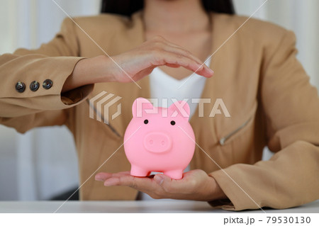 Young active business woman hands in casual dress sitting and protecting piggy bank on white table. Insurance and security concept. 79530130