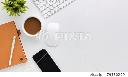 Top view white wooden workspace office desk with computer and office supplies. Flat lay work table with blank notebook, keyboard, green leaf and coffee cup. Copy space for your advertising content. 79530299