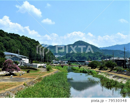 奈良県桜井市金屋、仏教伝来の地の立て札と石碑がある大和川沿いの河川敷の風景、遠くに山との山々が見える 79530348