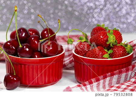 Juicy Fresh Strawberries and Sweet Cherry in a Red Bowls on piece of cloth on a silver sparkling background. Vitamin food 79532808