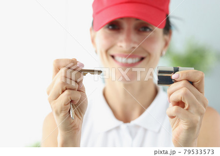 Smiling woman in red cap holding key and keyhole closeup Smiling woman in red cap holding key and keyhole closeup 79533573