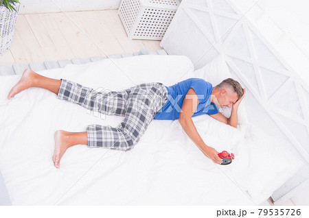It is time. Exhausted man being awakened by clock  79535726