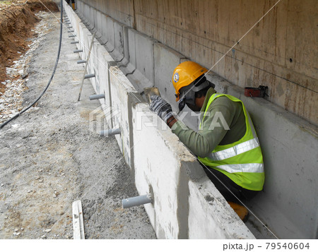 SELANGOR, MALAYSIA -DECEMBER 02, 2016: Construction workers laying precast concrete drain at the construction site. SELANGOR, MALAYSIA -DECEMBER 02, 2016: Construction workers laying precast concrete drain at the construction site. 79540604