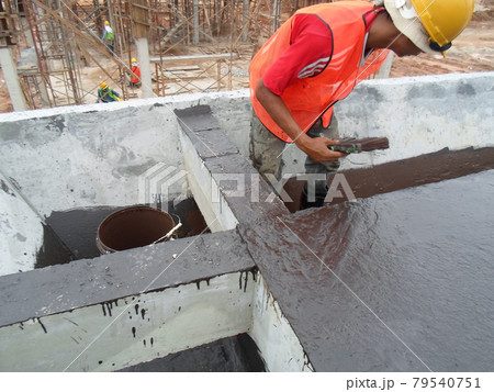 SELANGOR, MALAYSIA -SEPTEMBER 16, 2014: Construction worker apply layers of bituminous waterproofing at the building roof slab surface. 79540751