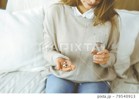 Close-up woman holding pills time to take medications, cure for headache, high blood pressure pain killer drugs at home. Stay at home concept during Coronavirus pandemic Close-up woman holding pills time to take medications, cure for headache, high blood pressure pain killer drugs at home. Stay at home concept during Coronavirus pandemic 79540913