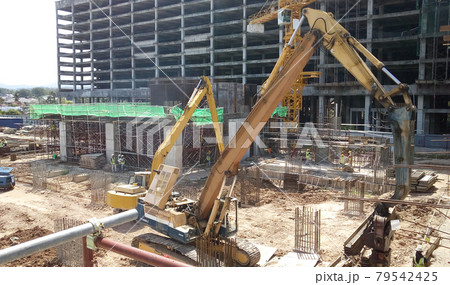 SELANGOR, MALAYSIA -APRIL 15, 2016: Sheet pile cofferdam driven machine at the construction site. The machine drove the sheet pile to the earth using vibrated hydraulic arm. Workers control. SELANGOR, MALAYSIA -APRIL 15, 2016: Sheet pile cofferdam driven machine at the construction site. The machine drove the sheet pile to the earth using vibrated hydraulic arm. Workers control. 79542425