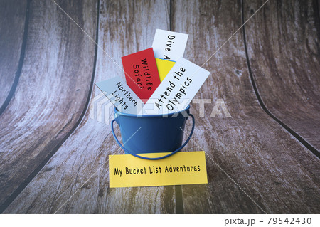 My bucket list adventures written on a colorful paper inside of a blue bucket 79542430