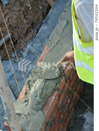 JASIN, MALAYSIA -SEPTEMBER 09, 2016: Brick walling joint and workmanship under construction at the construction site. Clay brick was attached together using cement mortar. JASIN, MALAYSIA -SEPTEMBER 09, 2016: Brick walling joint and workmanship under construction at the construction site. Clay brick was attached together using cement mortar. 79542504