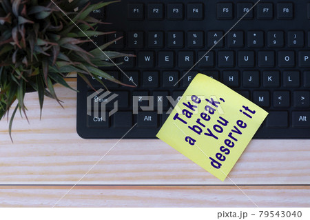 Text on yellow note with keyboard and potted plant on wooden table 79543040