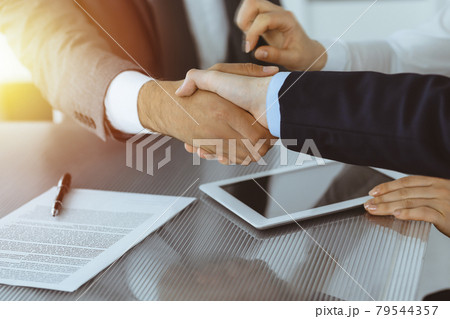Handshake as successful negotiation ending, close-up. Unknown business people shaking hands after contract signing in modern office Handshake as successful negotiation ending, close-up. Unknown business people shaking hands after contract signing in modern office 79544357
