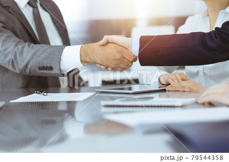 Handshake as successful negotiation ending, close-up. Unknown business people shaking hands after contract signing in modern office Handshake as successful negotiation ending, close-up. Unknown business people shaking hands after contract signing in modern office 79544358