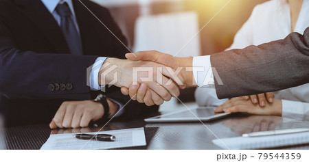 Handshake as successful negotiation ending, close-up. Unknown business people shaking hands after contract signing in modern office Handshake as successful negotiation ending, close-up. Unknown business people shaking hands after contract signing in modern office 79544359