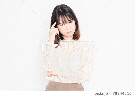 白背景の前に立って、悩んでいる、レースのブラウスを着た若い女性 79544516