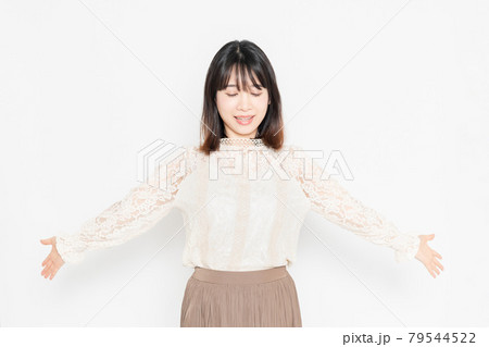 白背景の前に立って、深呼吸する、レースのブラウスを着た若い女性 79544522