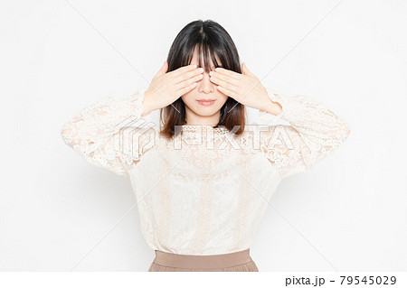 白背景の前に立って、目を隠す、レースのブラウスを着た若い女性 79545029