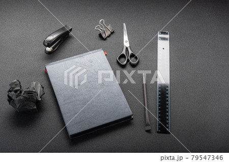 Black office supplies on a black table. Black ruler and black notebook. Front view at an angle. Black office supplies on a black table. Black ruler and black notebook. Front view at an angle. 79547346