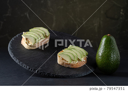 Sliced avocado into wedges. Avocado slices and a whole vegetable. Showcase with sandwiches. 79547351