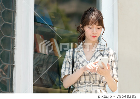 屋外でスマホを操作する若い私服のビジネスウーマン 屋外でスマホを操作する若い私服のビジネスウーマン 79548285