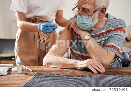 Man wearing protective mask receiving vaccine shot in hand Man wearing protective mask receiving vaccine shot in hand 79550408