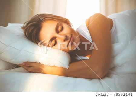 Beautiful blonde girl sleeping sweetly in sunny bedroom on a white bed. Holyday comfort and Rest concepts Beautiful blonde girl sleeping sweetly in sunny bedroom on a white bed. Holyday comfort and Rest concepts 79552141