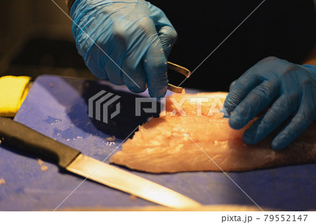 the chef cuts the fish in blue gloves the chef cuts the fish in blue gloves 79552147