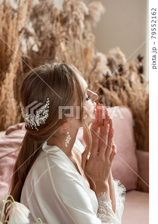 A girl with a beautiful hairdo and a decoration of beads in her hair. I put my hands to my face. The morning of the bride. 79552162