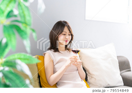家でワインを楽しむ若い女性 79554849