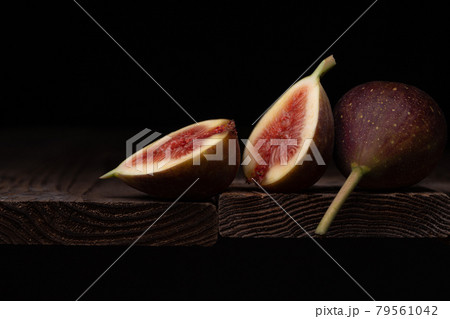 イチジクを半分に切って板の上に置いた写真、黒背景 79561042