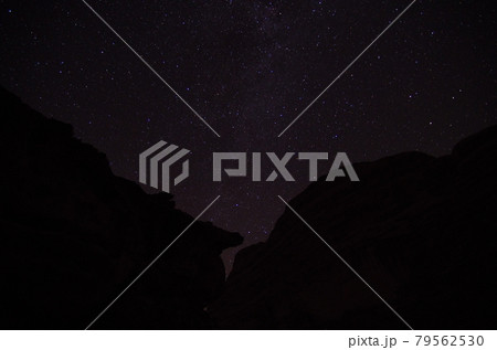 【ヨルダン】広大な砂漠ワディラム、真夜中に夜空に輝く星と岩陰 79562530