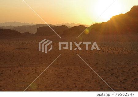 【ヨルダン】広大な砂漠ワディラム、岩山の奥に沈んでいく夕日と 79562547