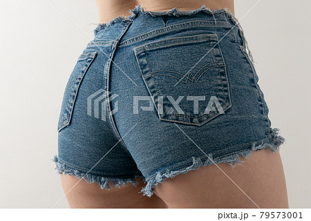 Back view of sexy girl showing her butt in tight white jeans shorts on white background. 79573001