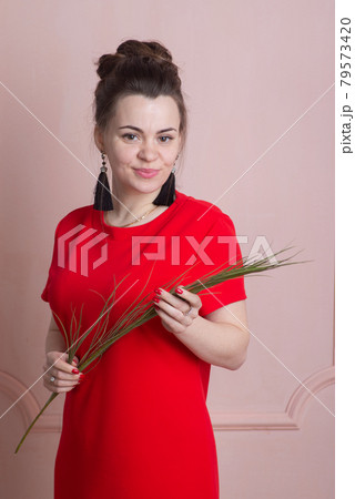 Beautiful woman in red dress posing against the wall in rococo style 79573420