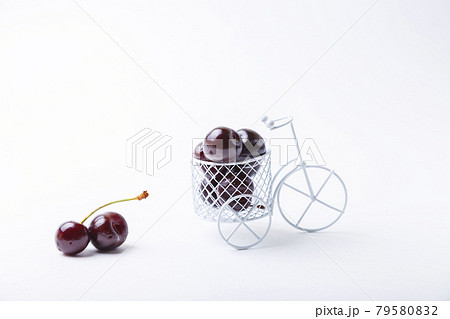 Cherry in a miniature bike. Toy bike with berries on a white background. Close-up, Copy space for text. Cherry in a miniature bike. Toy bike with berries on a white background. Close-up, Copy space for text. 79580832