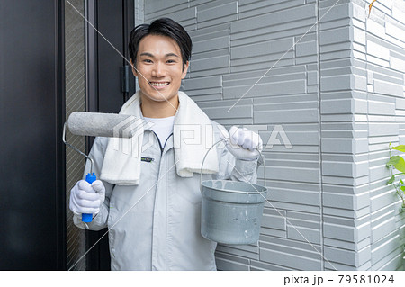 外壁塗装を終えて玄関の前で微笑む若い男性ペンキ職人 79581024