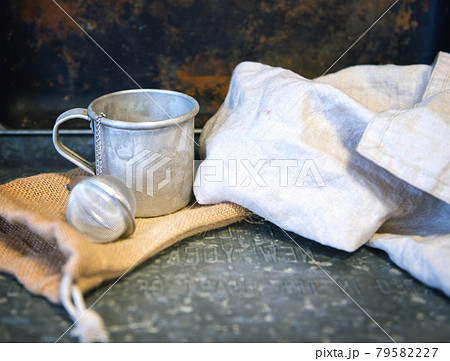 Metal teacup with tea egg behind the cotton white towel. rustic vintage style 79582227