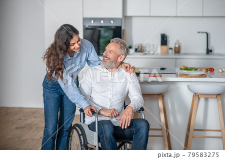 Young long-haired woman smiling nicely to her handicapped hausband and both looking happy 79583275