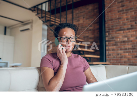 A woman in eyeglasses working on a laptop and talking on the phone A woman in eyeglasses working on a laptop and talking on the phone 79583300