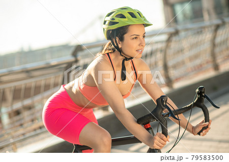 Female cyclist in bright sportswear riding a racing bike 79583500