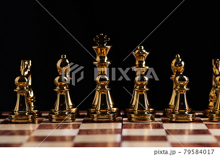 Golden chess figures standing on chessboard 79584017