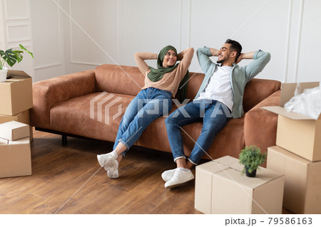Muslim family relaxing on couch in new home with boxes Muslim family relaxing on couch in new home with boxes 79586163