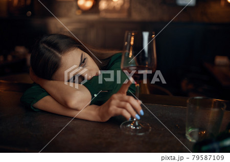 Depressed woman sitting in bar, full ashtray Depressed woman sitting in bar, full ashtray 79587109