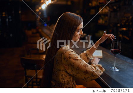 Alone woman with glass of wine sitting in bar 79587171
