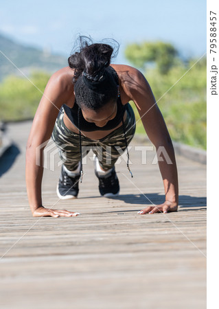 Strong afro american woman doing push ups on a wooden runway: Exercise and healthy lifestyle concept 79588457