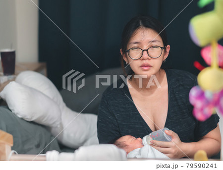 Tired asian mother feeding newborn baby from milk bottle at late night. Tired asian mother feeding newborn baby from milk bottle at late night. 79590241