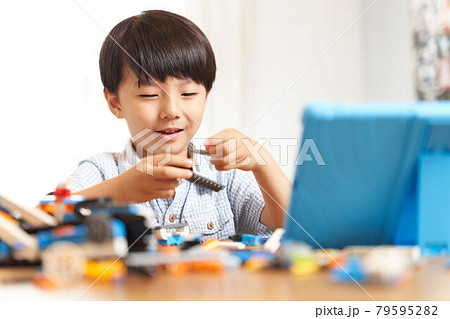 タブレットを見ながらプログラミング教材を組み立てる男の子 79595282