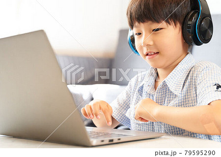 ヘッドフォンをつけてPCを操作する男の子 79595290