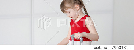 Little girl with blond hair opens yellow suitcase Little girl with blond hair opens yellow suitcase 79601819